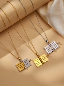 Detail view of book-shaped locket necklaces with engraved inspirational messages for daughters