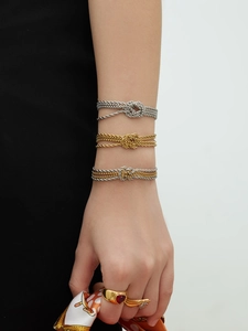 Tre bracciali in acciaio inossidabile con nodi in oro e argento indossati da modella