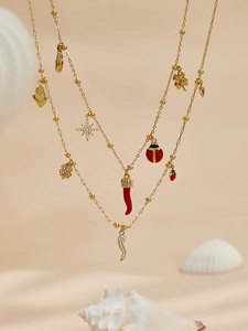 Détail des breloques trèfle et piment plaqués or 18 carats sur un ensemble bijoux