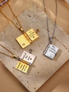 Detail of opening book pendants in gold and silver showing inner engraved quotes on chains