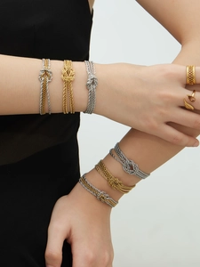 Primo piano di bracciali a catena con nodi e anelli testurizzati in oro 18k e argento