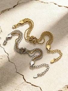 Dettaglio di bracciali a catena intrecciata in oro e argento con nodo su pietra