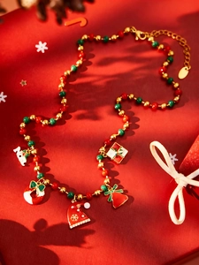 Detail van kerstkralenketting met kerstmuts, Joy-hanger en feestelijke bedeltjes