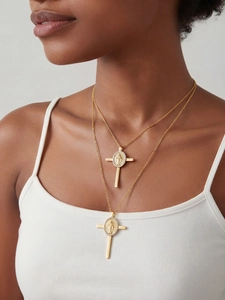 Dettaglio di un ciondolo a croce in acciaio placcato oro 18k con zirconi e icona religiosa