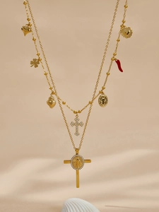 Dettaglio di una collana dorata a strati con croce in zircone e medaglie religiose
