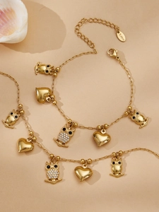 Detail von vergoldetem Edelstahl-Schmuckset mit Eulen- und Herzanhängern und Zirkon