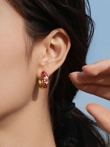 Detail of flower enamel hoop earring in 18k gold plated stainless steel on model