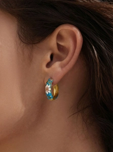 Detailed shot of enamel flower hoop earrings with blue glaze and 18k gold plating