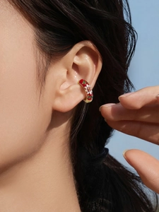 Close-up of red enamel flower ear cuff in gold finish worn on a woman ear
