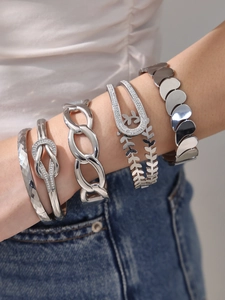 Detailaufnahme gestapelter Silberarmbänder mit Zirkon- und geometrischen Blattmotiven