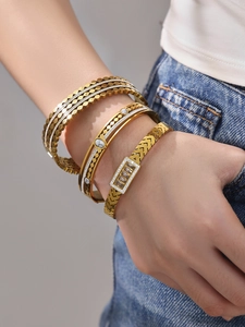Close-up of three gold-plated stainless steel bangles with zircon and marble inlay