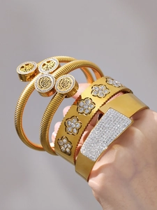 Dettaglio di bracciali in acciaio placcati oro 18k con albero della vita e motivi floreali