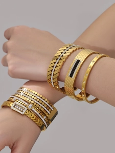 Macro shot of 18k gold plated stainless steel bangles with zircon inlay and geometric textures