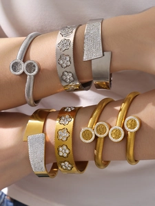 Dettaglio di bracciali in acciaio inox oro e argento con albero della vita e fiori
