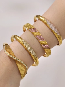 Close-up of stacked 18k gold plated bangles with colorful zircon inlay and wavy design