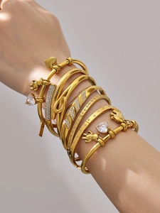 Close-up of stacked 18k gold plated bracelets with 5A zircon hearts and bear charms