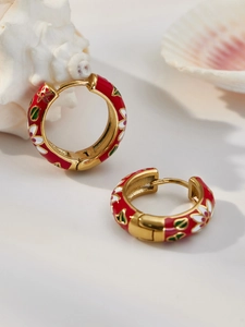 Detail of red enamel floral hoop earrings with 18k gold plating on a white surface