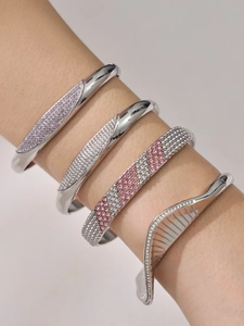 Close-up of stacked stainless steel bangles with pink and white zircon inlays