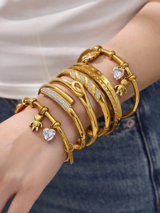 Detail of stacked 18k gold plated stainless steel bracelets with zircon and bear charm