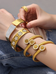Dettaglio del set di bracciali in oro e acciaio con ciondoli albero della vita e fiori