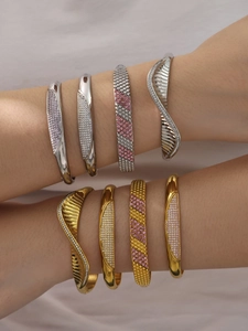 Close-up of stacked gold and silver bracelets with inlaid zircon stones on wrist