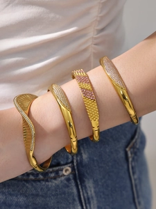 Detailed close-up of stacked gold-plated bangles featuring zircon inlays and geometric patterns