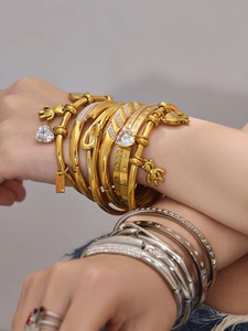 Close-up of stacked stainless steel bracelets with 18k gold plating and zircon stones