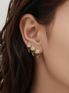 Gros plan de trois boucles d'oreilles goutte avec zircons blancs et noirs sur le modèle