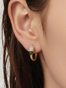 Gros plan de boucles d'oreilles goutte en or serties de zircons noirs et blancs