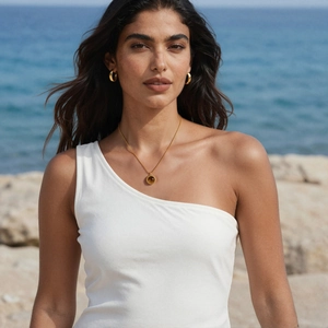 Détail du collier avec pendentif œil de tigre plaqué or 18k et créoles sur la plage