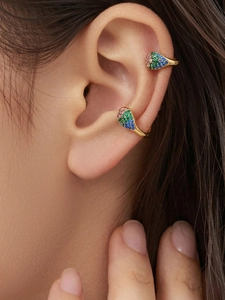 Détail de boucles d'oreilles dorées avec des pierres zircons roses, vertes et bleues