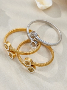 Dettaglio dei bracciali a serpente in oro e argento con ciondoli scintillanti Albero della Vita