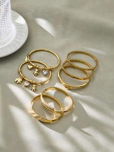 Detailed arrangement of 18k gold plated stainless steel bangles with zircon charms on velvet