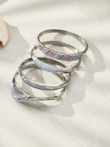 Detail of silver bangles with pavé zirconia settings and wave textures on sand