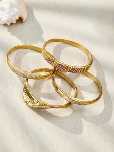 Detail view of four-piece gold stackable bracelets with sparkling zircon stones and shell decor