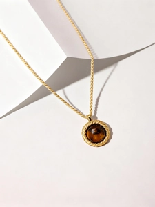 Détail de la chaîne torsadée dorée 18 carats et du pendentif rond en œil de tigre