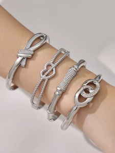 Close-up of four silver stacking bracelets with bow, double heart and infinity designs