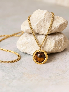 Vue rapprochée d'un collier chaîne torsadée plaqué or 18k avec pendentif en œil de tigre