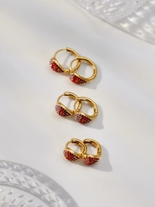 Détail de trois paires de créoles dorées avec strass en dégradé de rouge et rose
