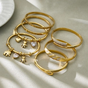 Stack of 18k gold plated stainless steel bangles with heart, bear, and zircon charms