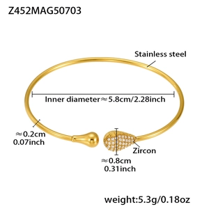 Detail of gold stainless steel wave bangle with cubic zirconia water drop accents