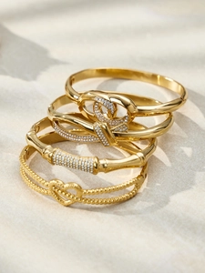 Close-up of set of four gold-plated bangles featuring zircon heart and knot designs