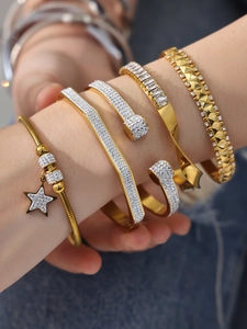 Gros plan de bracelets dorés et argentés superposés avec zircons 5A et pendentif étoile