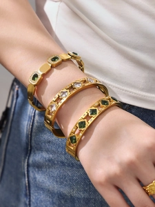 Close-up of three 18k gold plated stainless steel bangles with emerald and star cutouts