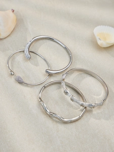 Close-up of silver stainless steel bracelets with wavy lines and crystal pavé details
