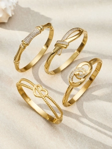 Detail of four-piece 18k gold plated bracelet set with cubic zirconia on sand background
