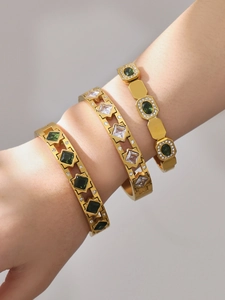 Detailed view of three 18k gold plated bangles with green and clear zircon gemstones
