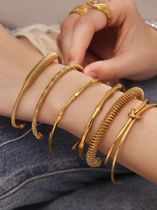 Detailopname van gestapelde gouden armbanden met bamboetextuur en spiraalvormen