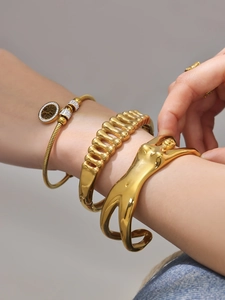 Dettaglio di bracciali sovrapposti placcati oro 18k con ciondolo albero della vita e zirconi