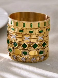 Detailed close-up of 18k gold plated bangles with emerald and zircon geometric stones